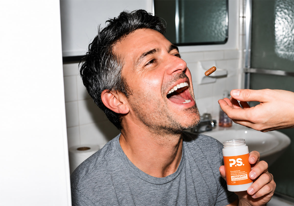 Man laughing as a P.S. Longevity capsule is tossed toward his mouth, holding the bottle